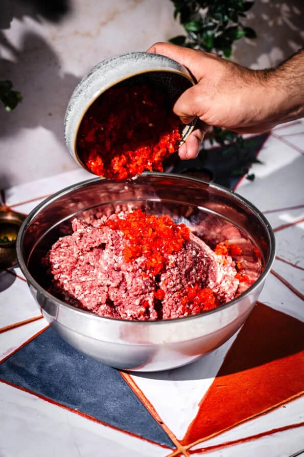 Red Peppers added to Lamb Meat in bowl