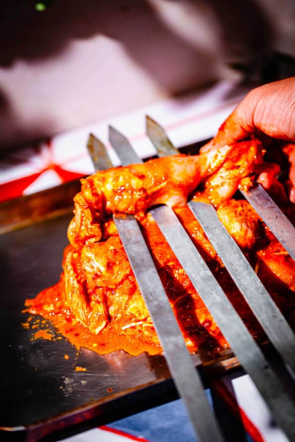 Chicken being added to skewers