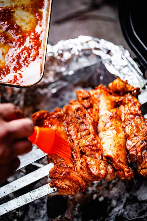 Chicken being basted on bbq