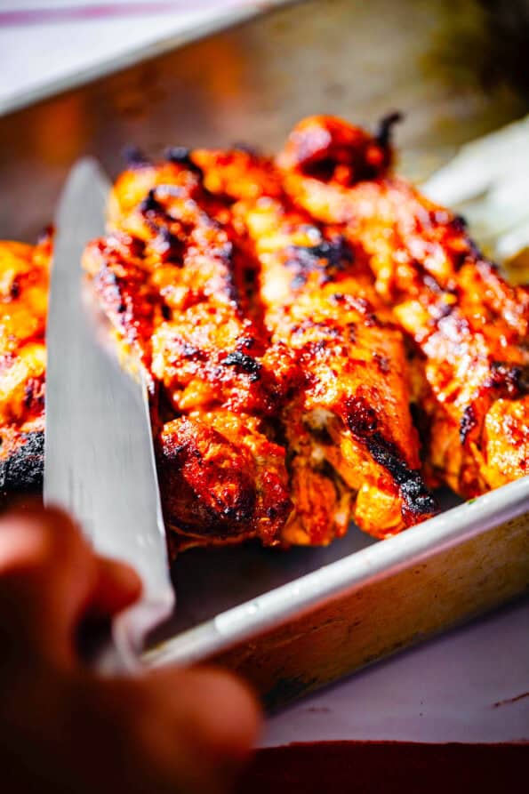 Chicken being sliced off skewers