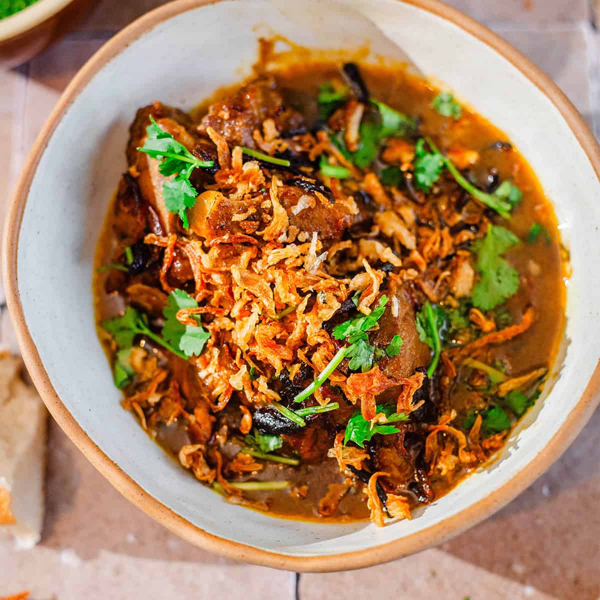 Authentic Pakistani Nihari (Slow-Cooked Beef Nihari) NIhari in a bowl with fried onions and coriander on top