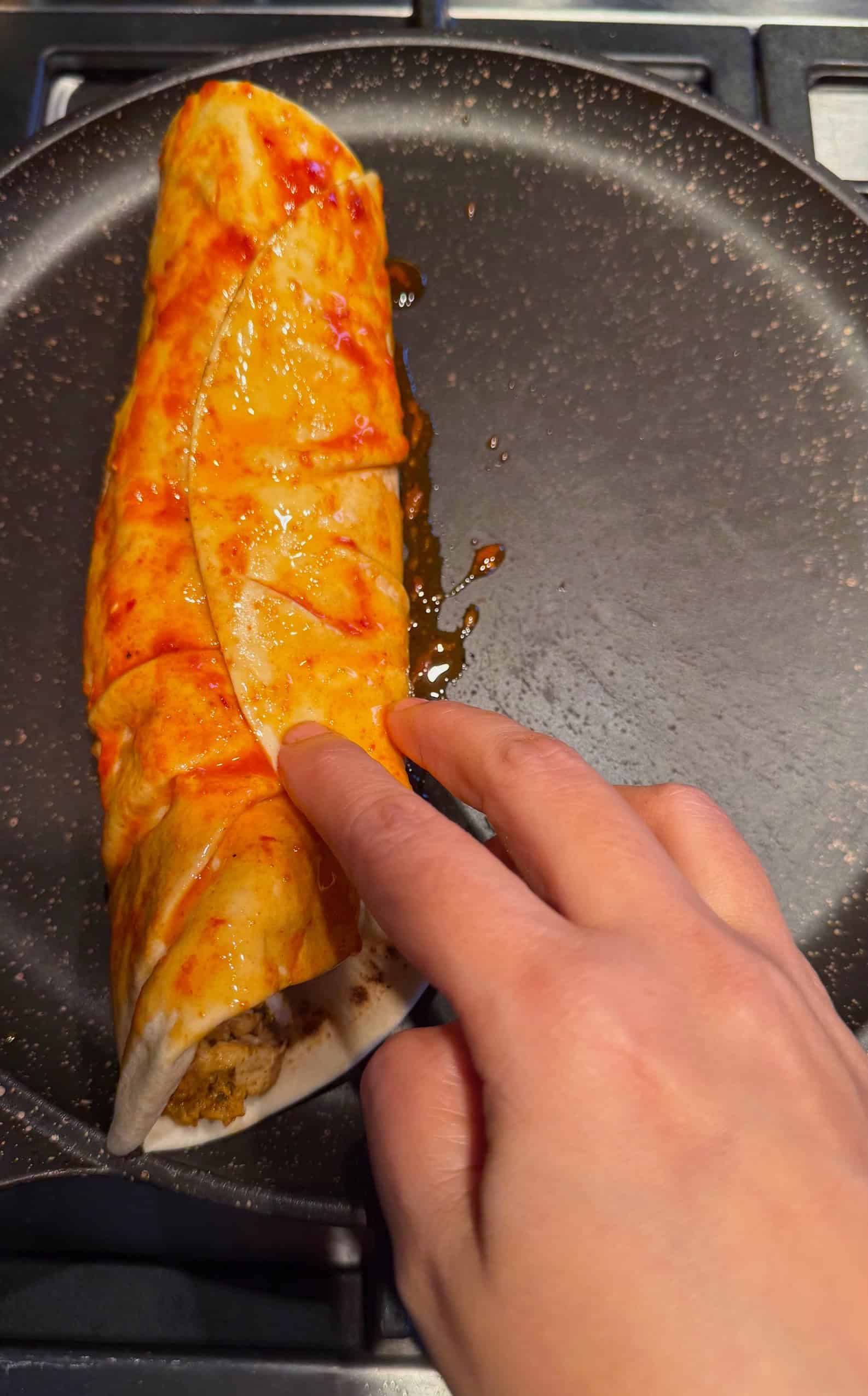 Crispy Chicken Shawarma Wrap with Toum and Pomegranate Molasses Wrap covered in sauce in pan