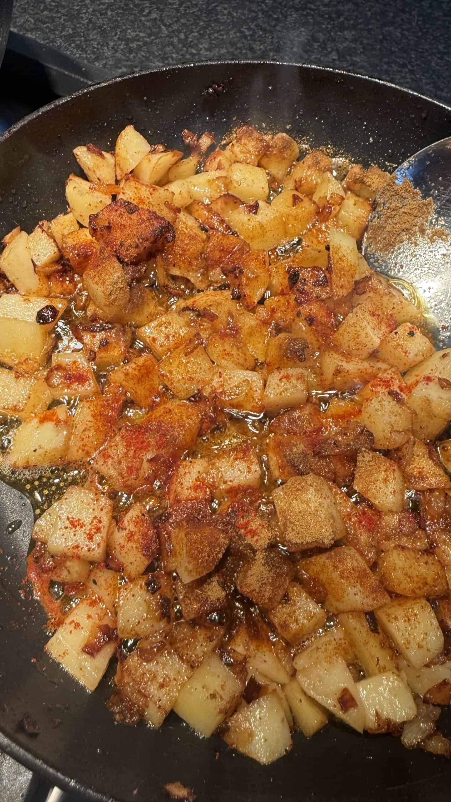 Lebanese Batata w Bayd – Potatoes and Eggs Spices added to potatoes in pan