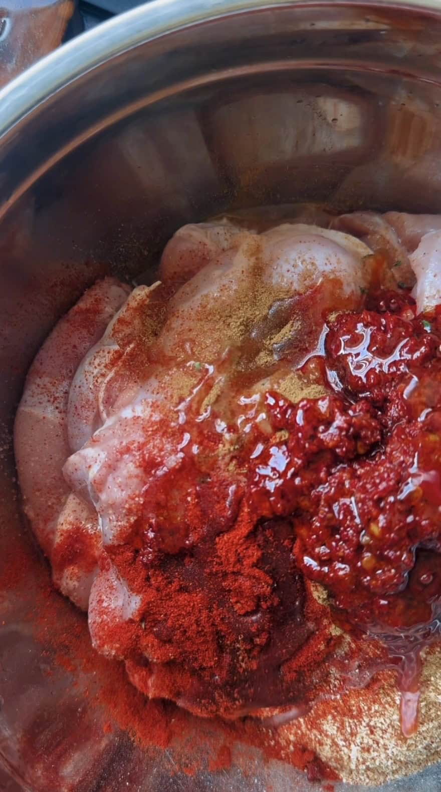 Harissa Chicken Thighs (Easy Oven-Baked Recipe) Olive oil added to bowl with thighs
