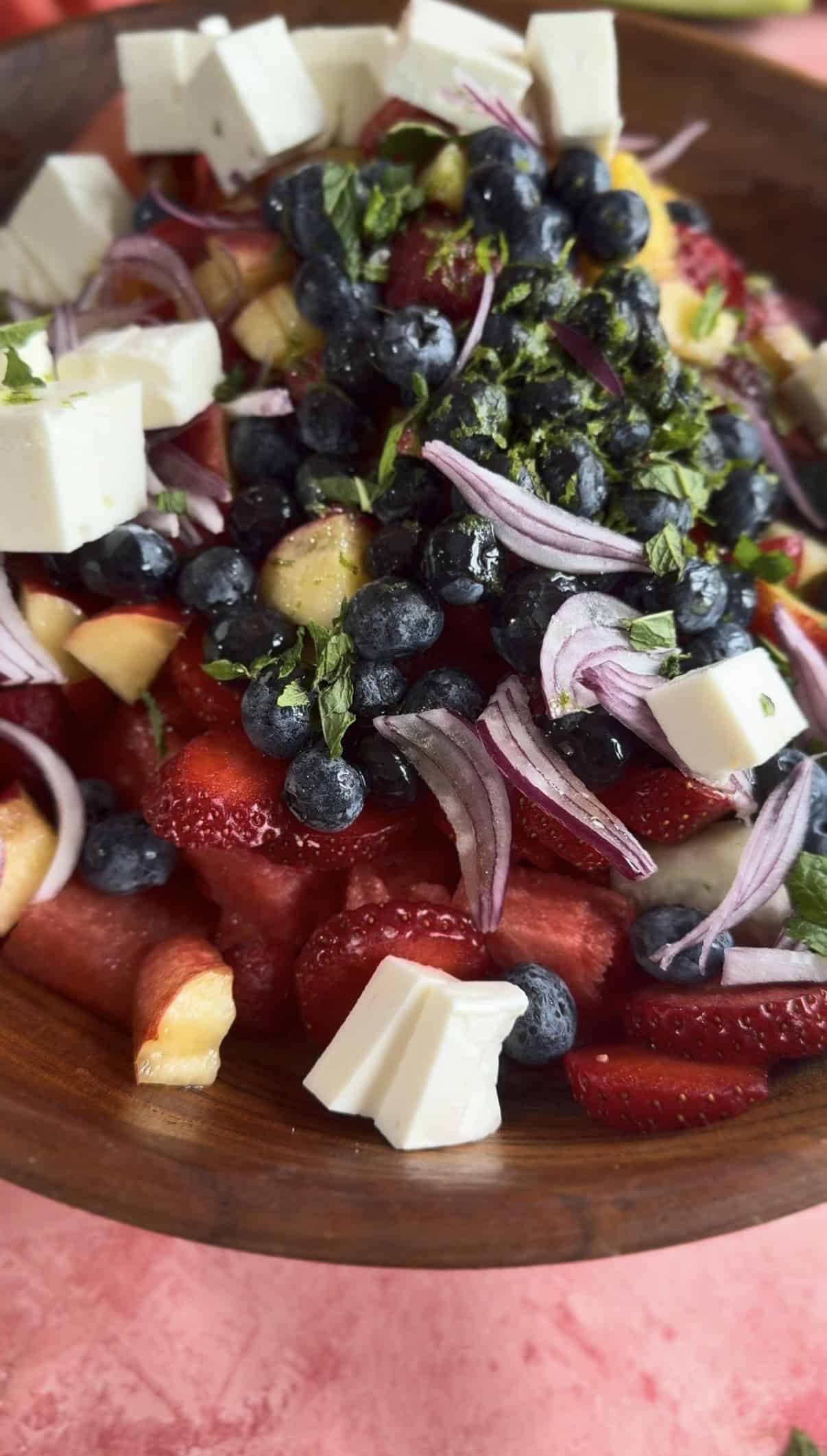 Summer Berry Watermelon Salad with Feta Onions, Feta and dressing added to bowl