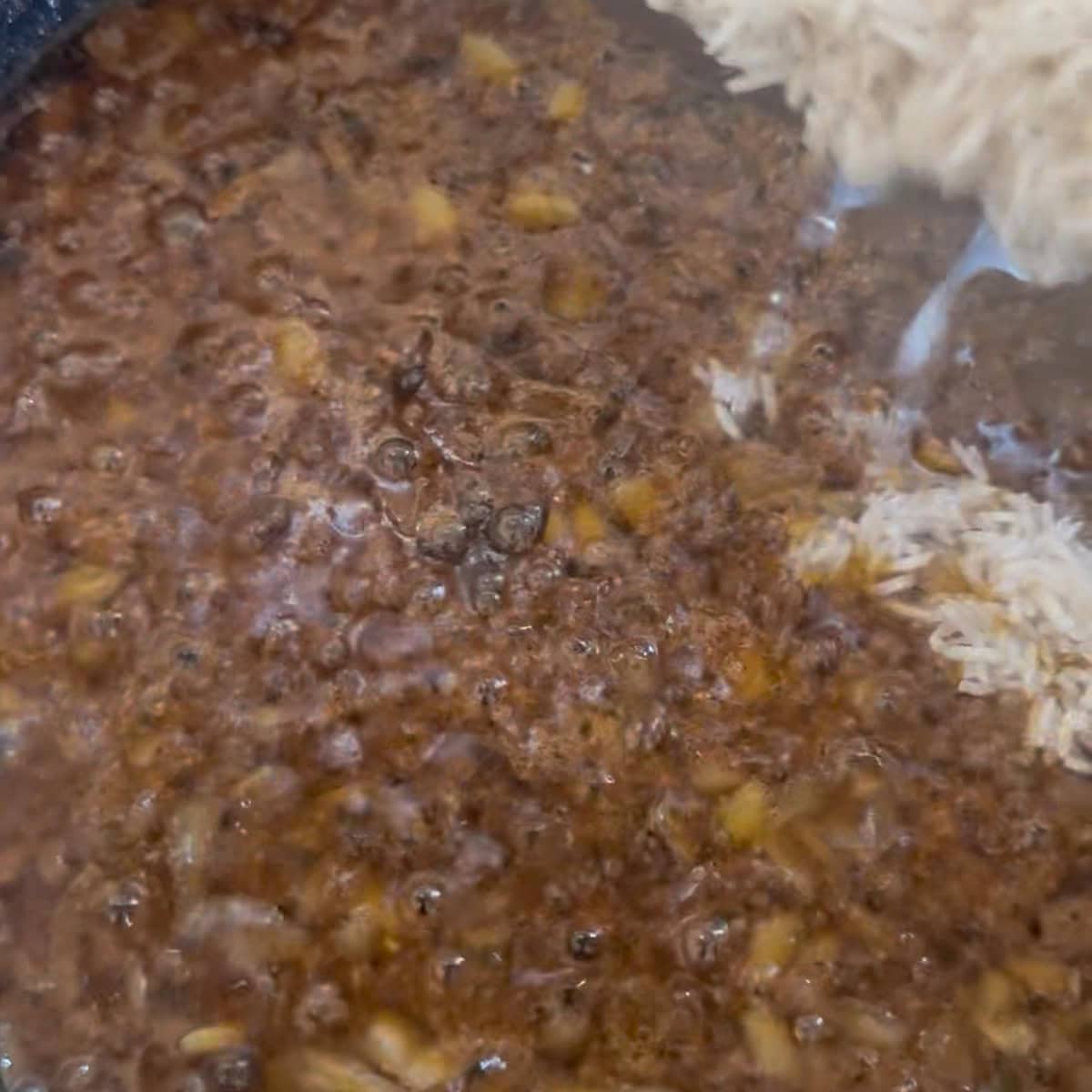 Browned onions in pot, rice being added