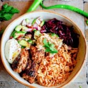 Kofta, rice, hummus, salad, tahini sauce and pickles in bowl